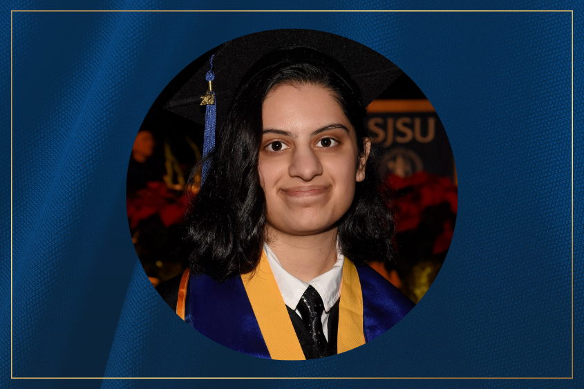 A graduate wearing a cap and gown with a blue and gold stole, posed against a festive background of flowers and university insignia.